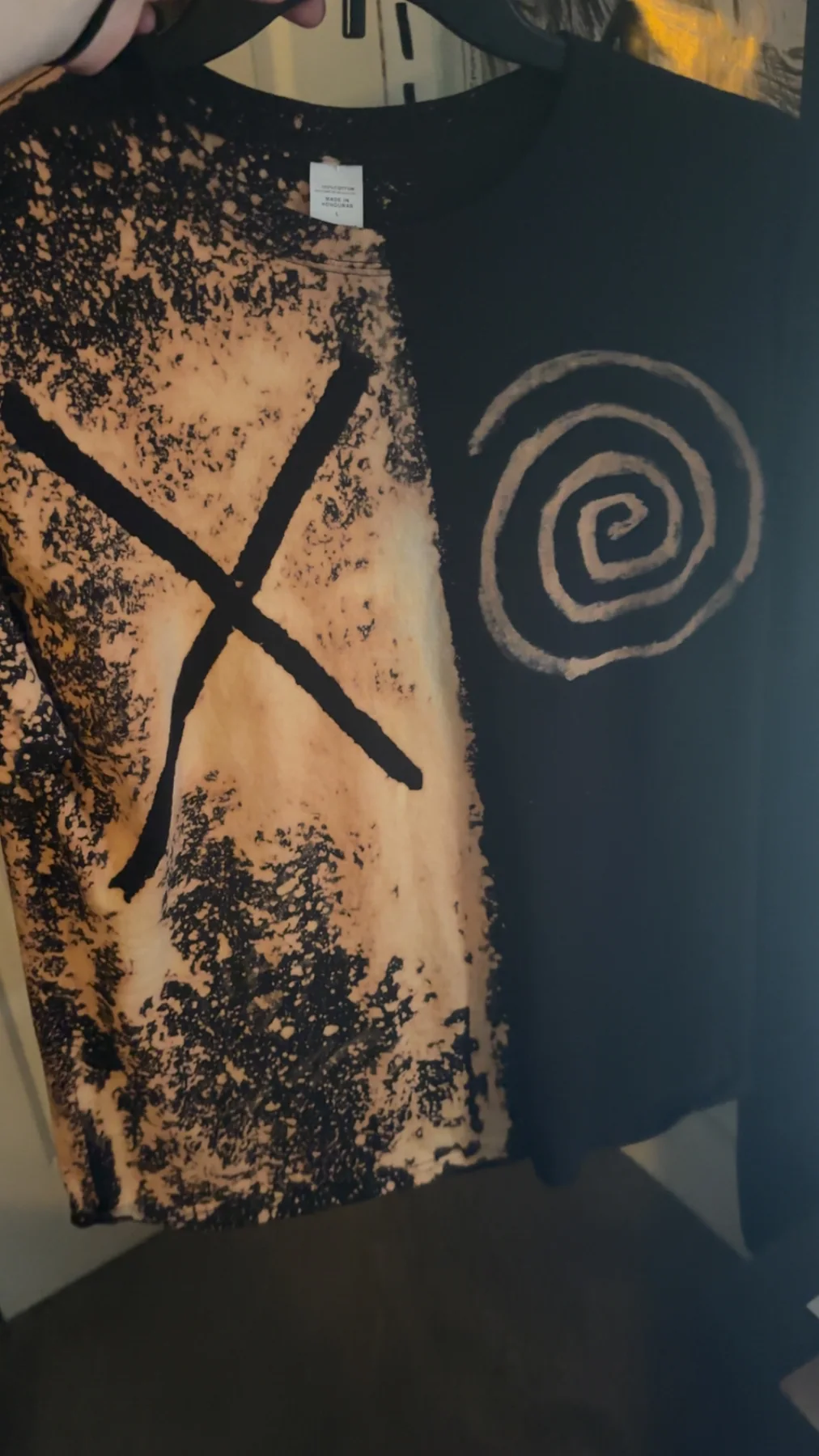 Black and bleach-dyed handmade shirt with an X and spiral design